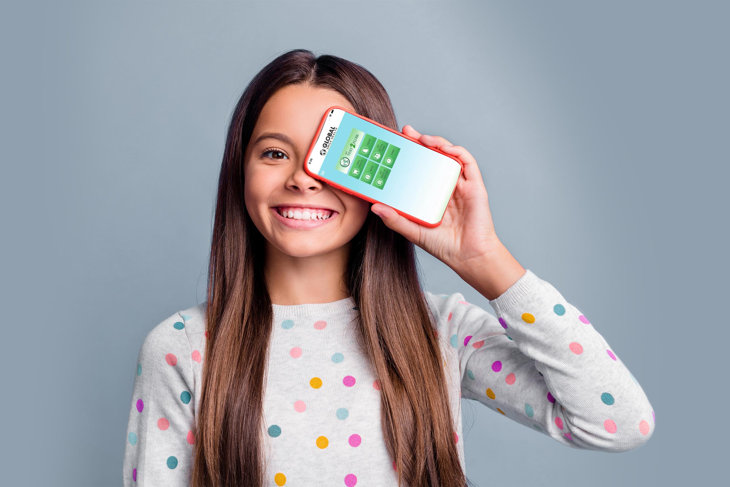 Photo portrait of happy girl covering one eye with phone with blank space isolated on bright purple colored background.